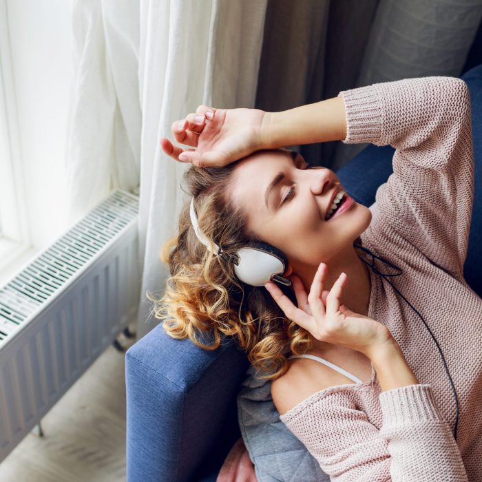 mulher deitada no sofá ouvindo música no headphone